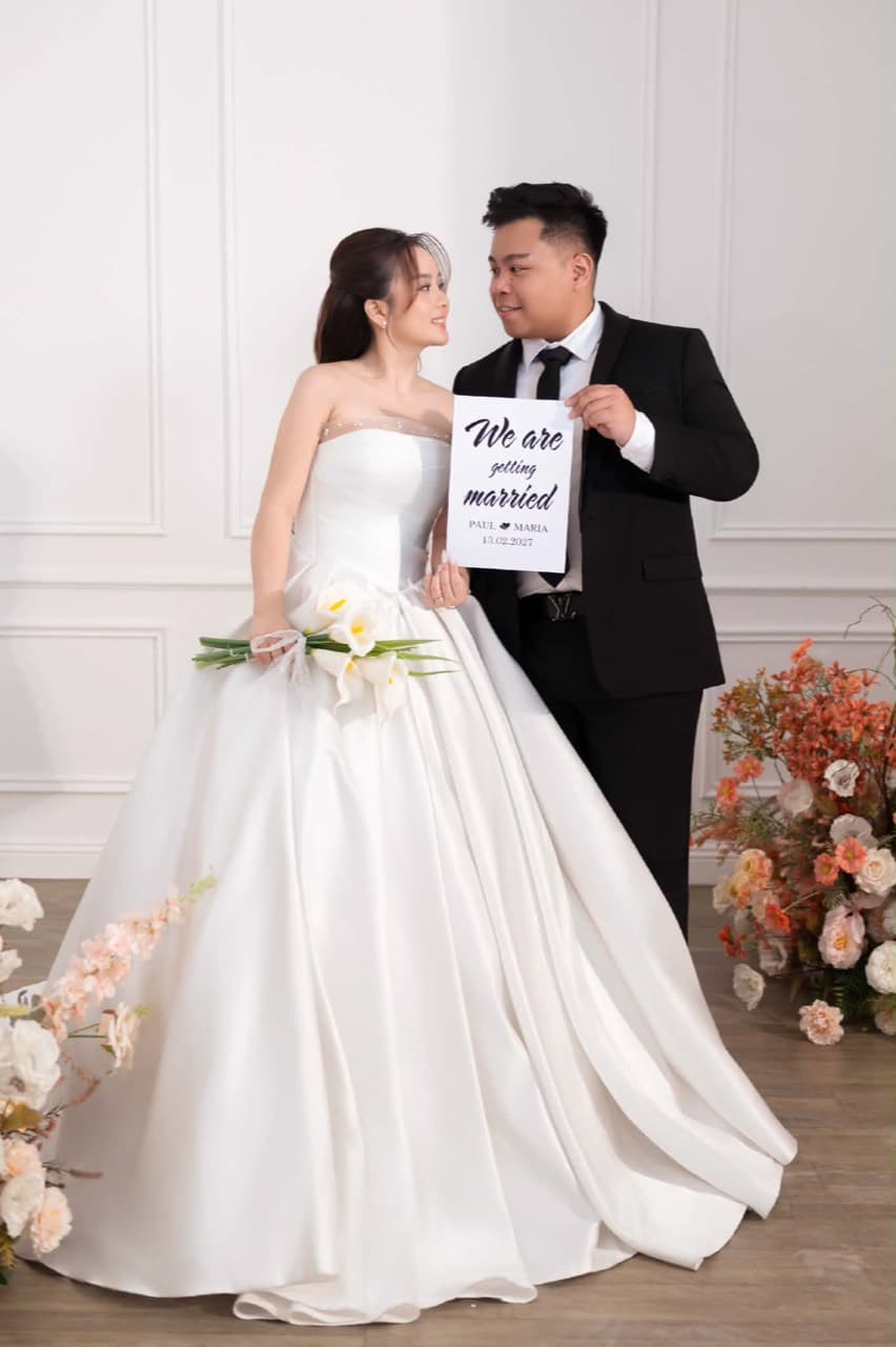 Paul and Maria looking at each other, holding their wedding announcement