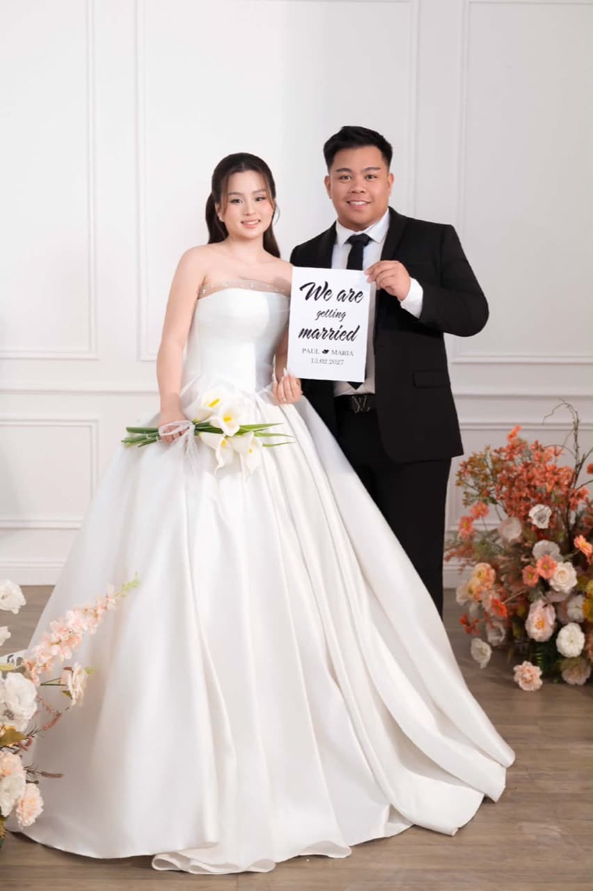 Paul and Maria smiling with their wedding announcement